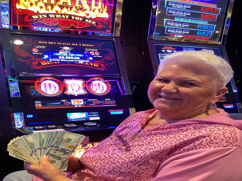 Woman in pink shirt posing after winning $2,500 at a slot machine.