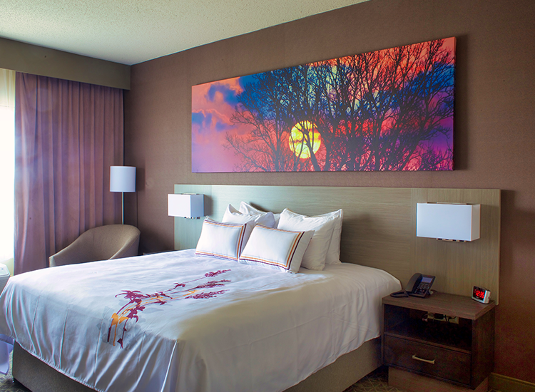 A modern hotel room featuring a bed with white bedding and decorative red accents.
