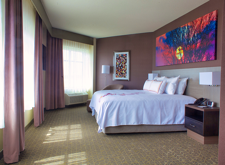 A modern hotel room featuring a bed with white bedding and decorative red accents. T